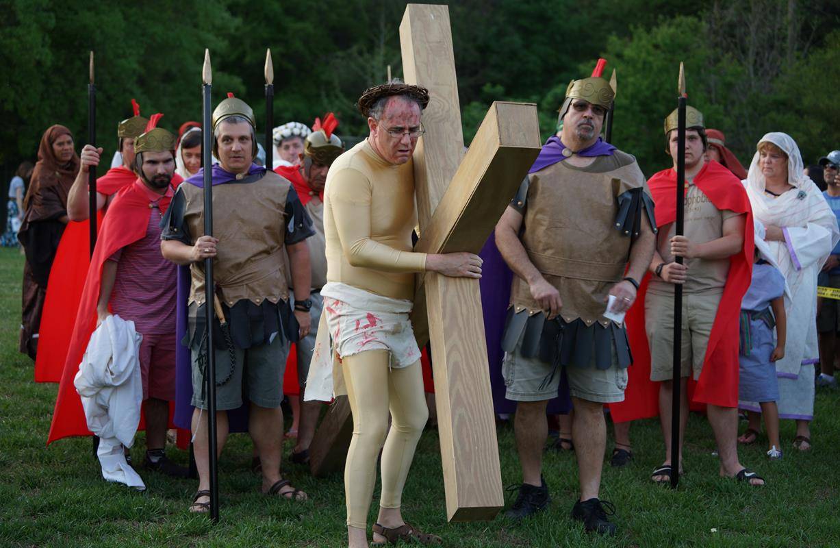 CHARLOTTE — Father Patrick Hoare and parishioners at St. John Neumann perform a Stations of the Cross.  (By John Cosmas) 
