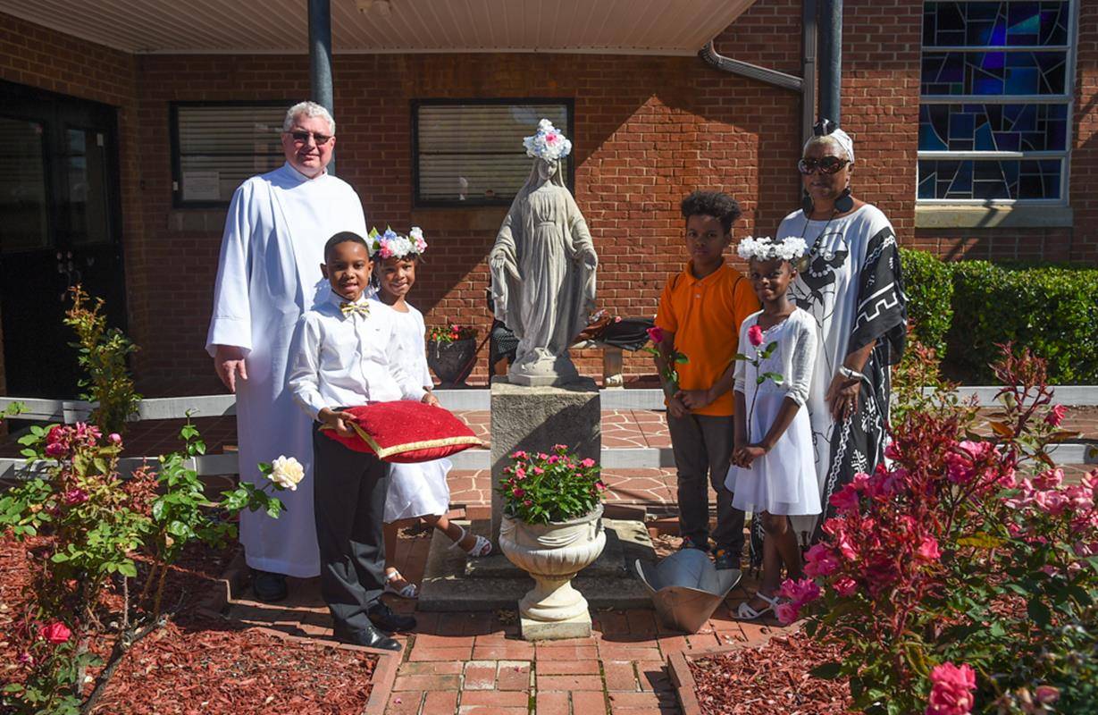 CHARLOTTE — May crowning at Our Lady of Consolation Church in May 14: Some of this year’s first Communicants are pictured with Father Carl Del Giudice, pastor. (Photos by Travis Burton | Catholic News Herald)